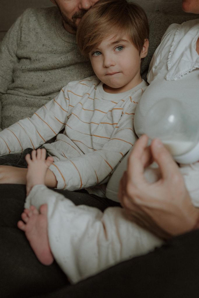 Ein Junge in gestreiftem Oberteil sitzt auf dem Schoß eines Erwachsenen.