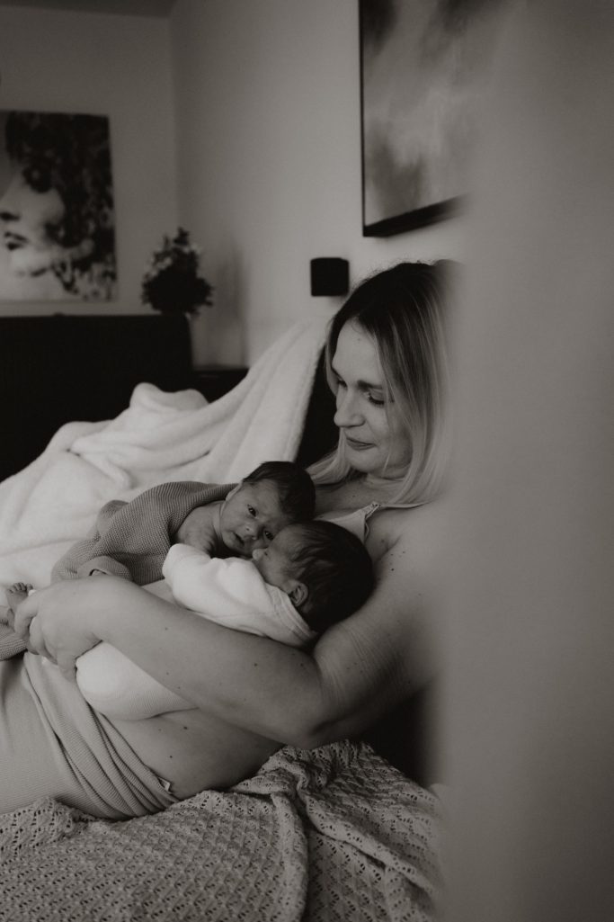 Eine Mutter hält liebevoll ihre zwei Säuglinge in den Armen.